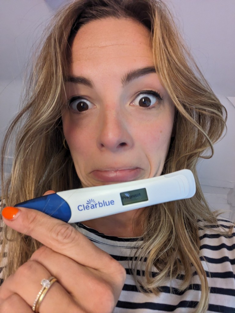 Shocked woman showing positive pregnancy text